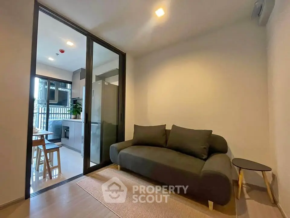 Modern living room with sleek sofa and open kitchen layout in a stylish apartment.