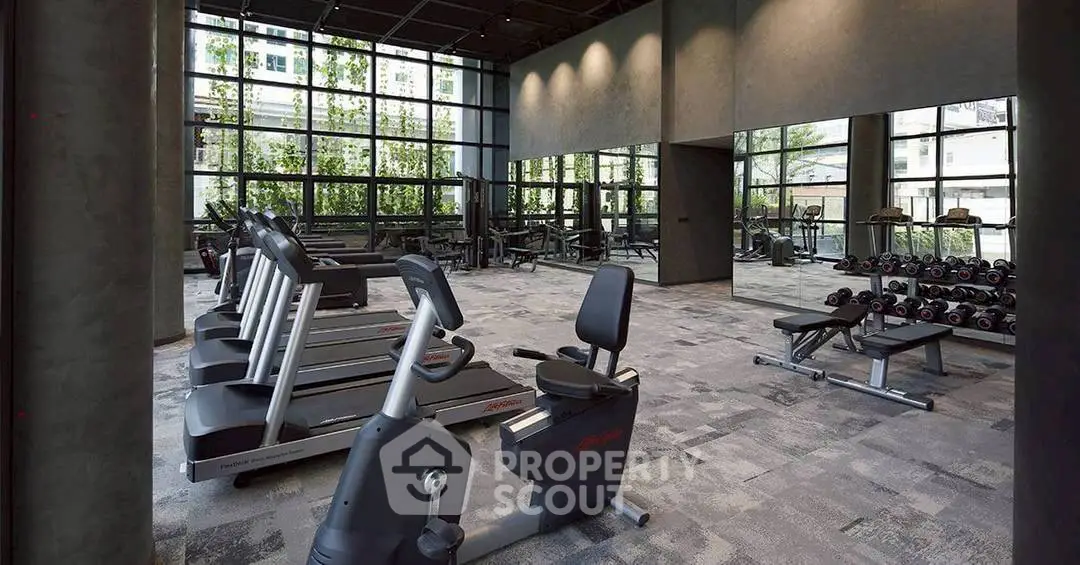 Modern gym with state-of-the-art equipment and large windows in luxury apartment complex.