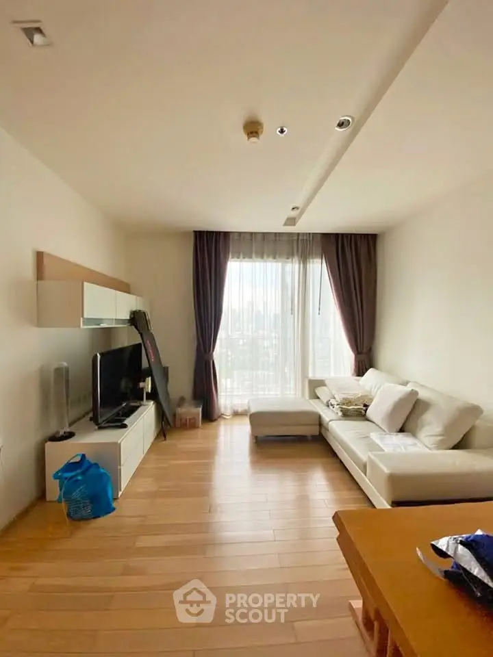 Spacious living room with modern decor and large window offering city views.