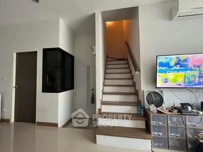Modern interior with staircase and wall-mounted TV in a stylish living space.