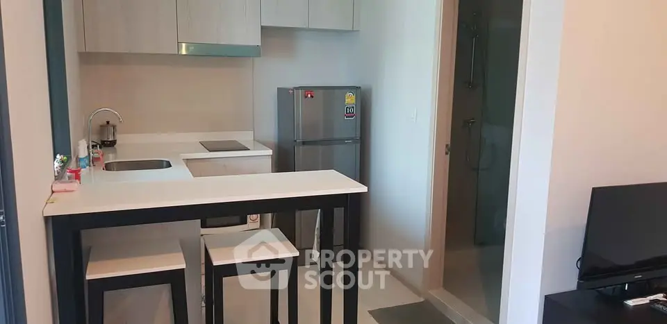 Modern compact kitchen with breakfast bar and sleek appliances in cozy apartment