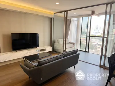 Spacious living room with modern furniture, large windows offering city views, and elegant lighting.