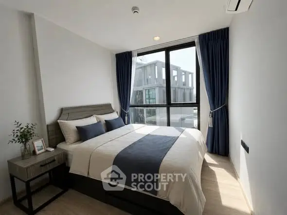 Modern bedroom with large window and stylish decor in a contemporary apartment.