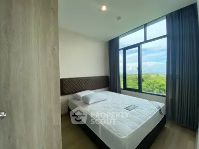 Modern bedroom with large window offering stunning green view, featuring a comfortable bed and stylish decor.