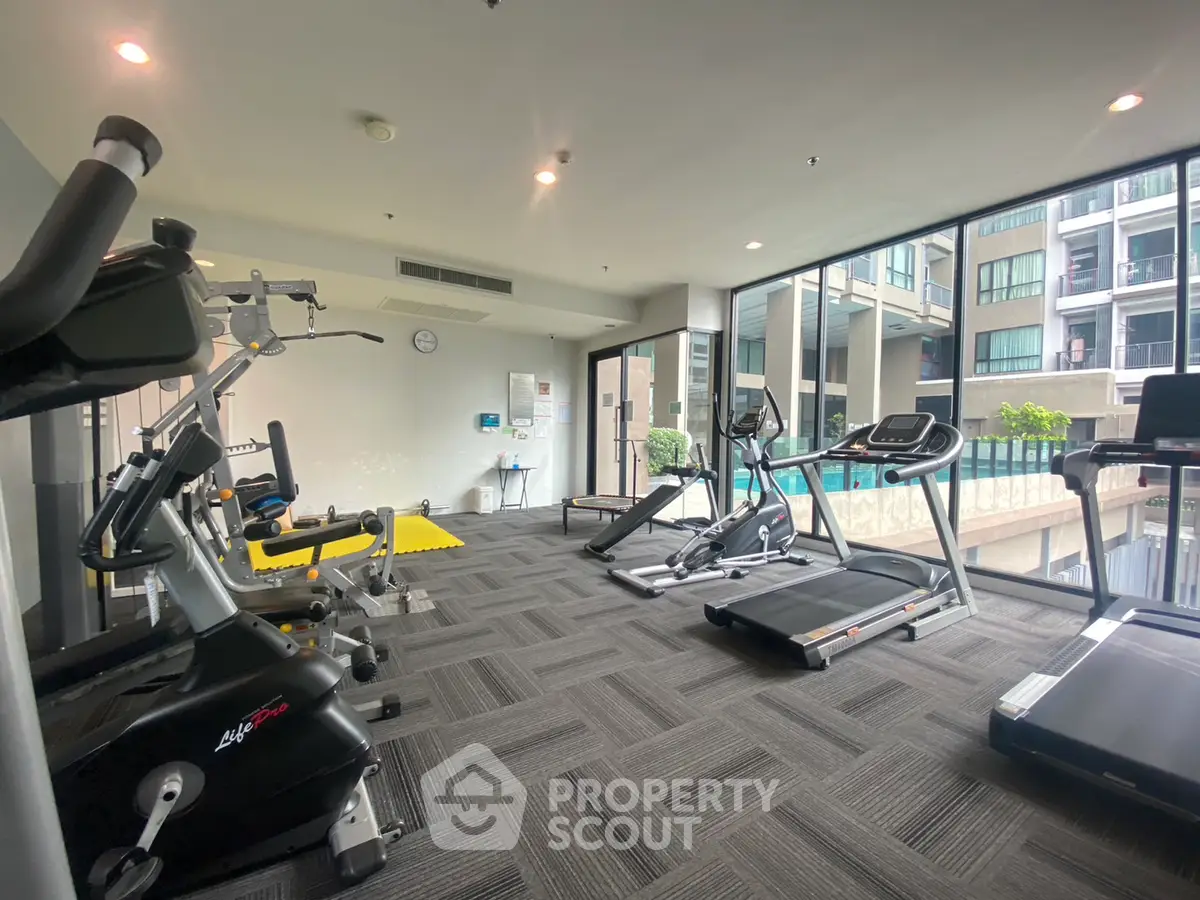 Modern gym with pool view in luxury apartment complex