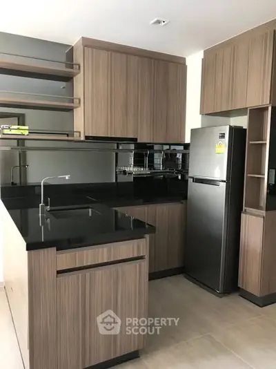 Modern kitchen with sleek wooden cabinets and stainless steel appliances, featuring a stylish black countertop.