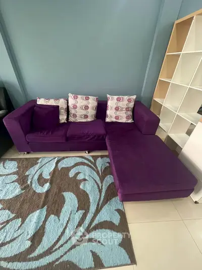 Stylish purple sectional sofa with patterned cushions in modern living room setting.