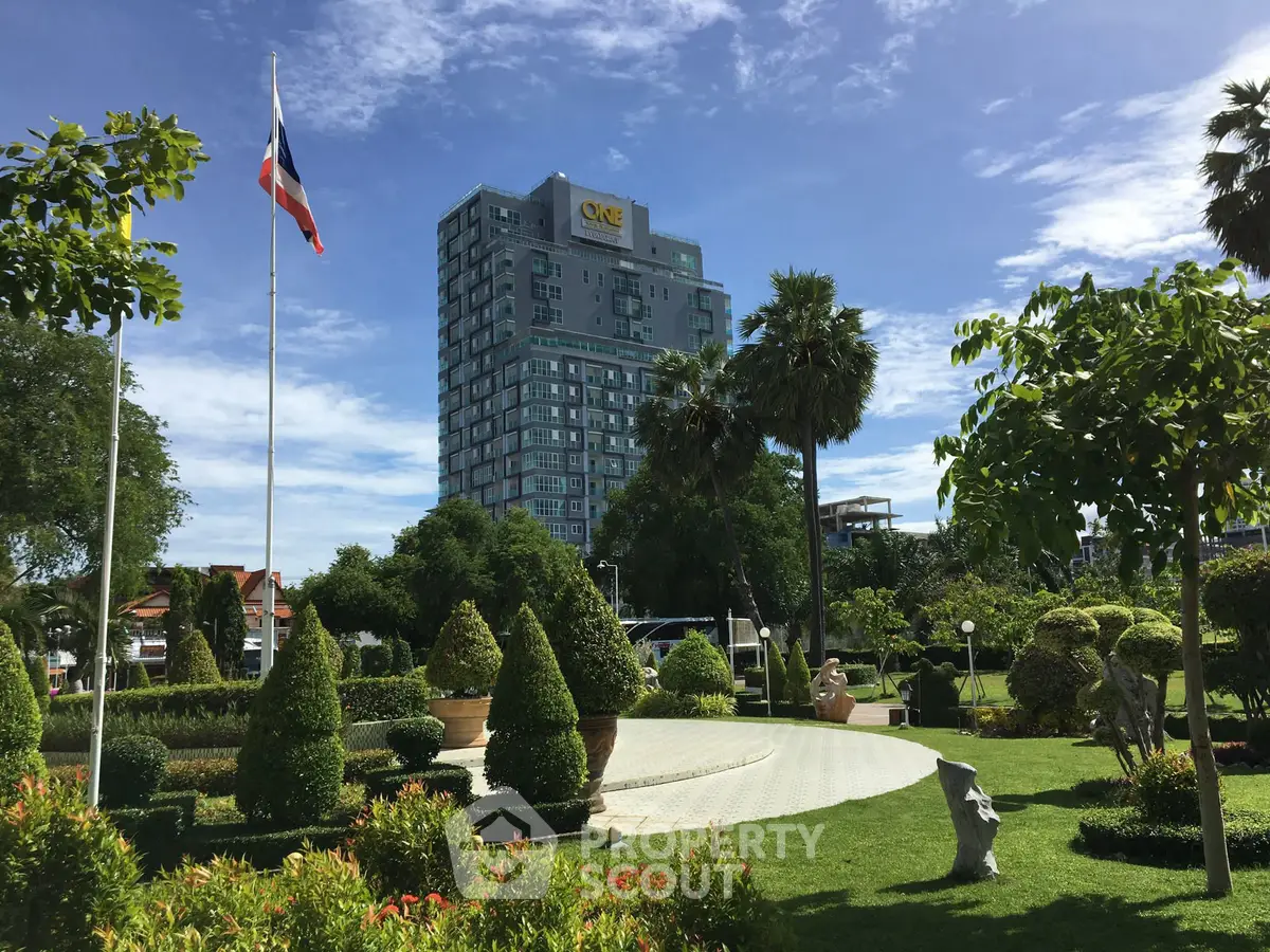 Luxurious high-rise building with lush landscaped garden and clear blue sky.