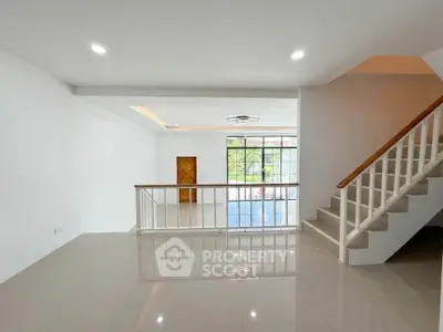 Spacious modern living room with staircase and large windows for natural light.