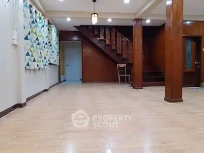 Spacious interior with wooden staircase and tiled floor, ideal for versatile living space.