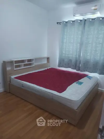 Cozy bedroom with wooden flooring and modern bed frame, perfect for relaxation.
