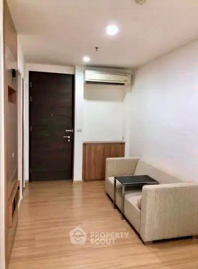 Cozy living room with modern furniture and wooden flooring, featuring a sleek air conditioning unit.