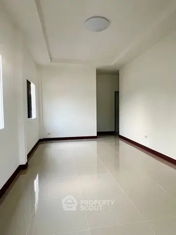 Spacious empty room with glossy tiled flooring and white walls