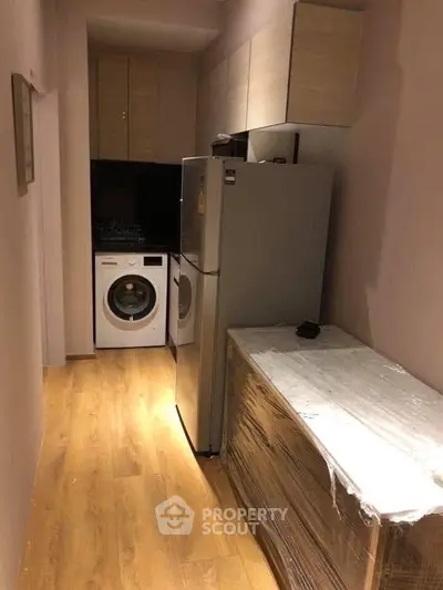 Compact kitchen with modern appliances including fridge and washing machine in cozy apartment.