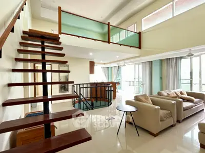 Spacious modern living room with open staircase and large windows offering natural light.
