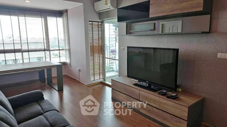 Modern living room with large TV and stylish furniture, featuring floor-to-ceiling windows for natural light.