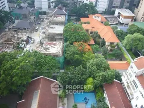 Aerial view of urban residential area with lush greenery and swimming pool.