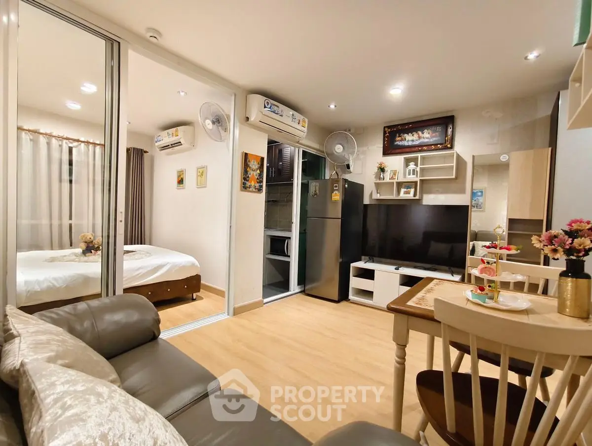 Modern open-plan living room with cozy decor and kitchen area in stylish apartment.