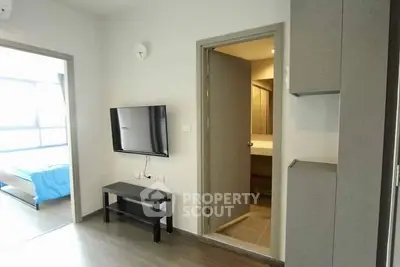 Modern apartment interior with wall-mounted TV and view into bedroom and bathroom.