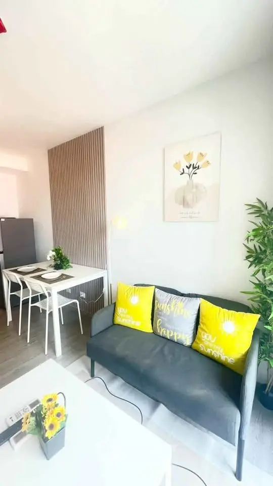 Bright modern living room with stylish decor and dining area, featuring a cozy sofa and vibrant cushions.