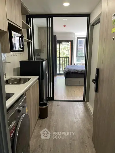 Modern studio apartment with compact kitchen and cozy bedroom, featuring a balcony with a view.