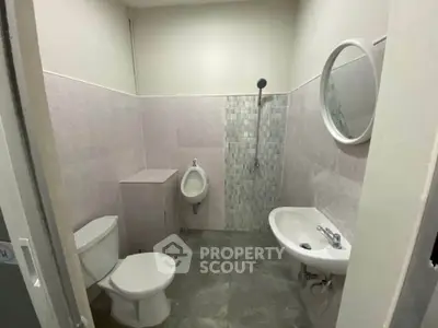 Modern bathroom with sleek fixtures and minimalist design, featuring a wall-mounted urinal and round mirror.