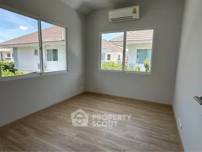 Bright empty room with wooden flooring and large windows in modern home