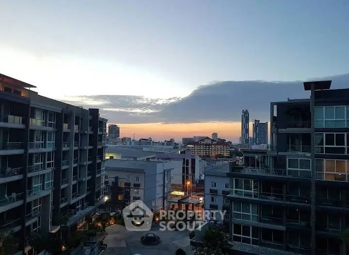 Stunning urban view from a high-rise apartment at sunset, showcasing modern cityscape.