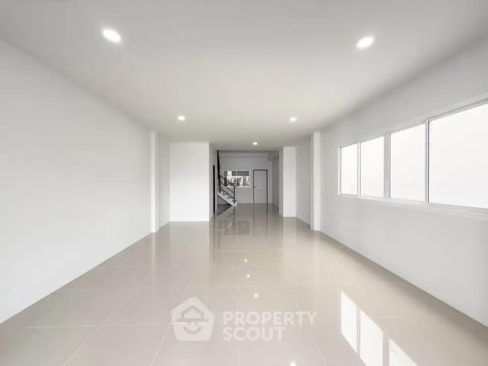 Spacious modern living room with sleek tile flooring and ample natural light.