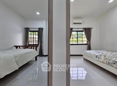 Spacious dual-bedroom setup with large windows and modern decor