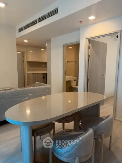 Modern apartment interior with open layout dining area and kitchen, featuring sleek furniture and contemporary design.
