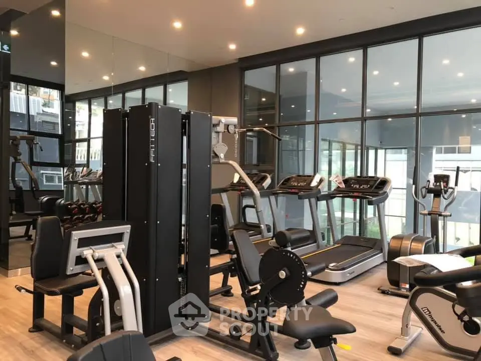 Modern gym with state-of-the-art fitness equipment and large windows in a luxury residential building.