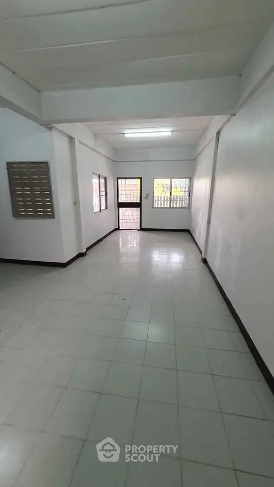Spacious empty room with tiled flooring and large windows, ideal for customization.