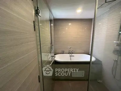 Modern bathroom with glass shower and built-in bathtub, featuring sleek tile design.