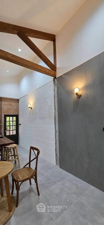 Modern interior with high ceilings and wooden beams, featuring stylish lighting and minimalist decor.