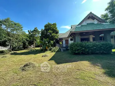 Charming countryside home with lush garden and spacious lawn under clear blue sky.