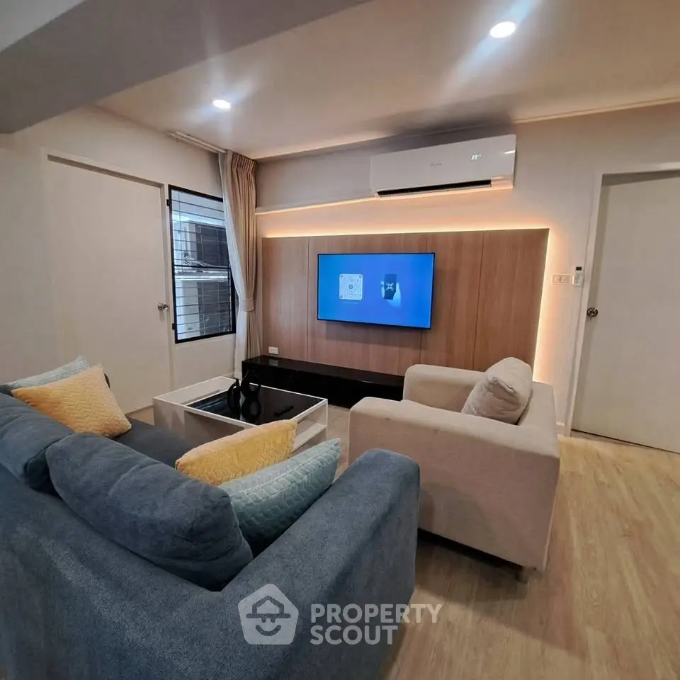 Modern living room with stylish furniture and wall-mounted TV, featuring cozy seating and ambient lighting.