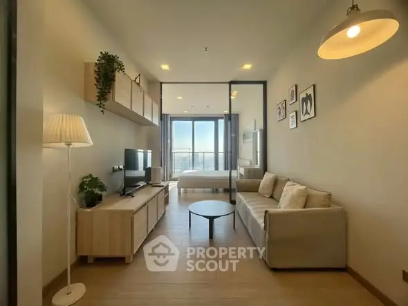 Modern living room with cozy sofa and TV, leading to a bright bedroom with city view.