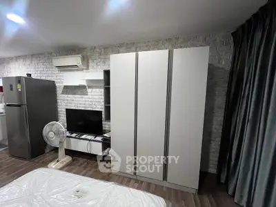Modern studio apartment with sleek furniture and air conditioning, featuring a wardrobe and entertainment center.
