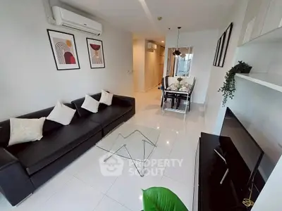 Modern living room with sleek black sofa and glass coffee table in a stylish apartment.