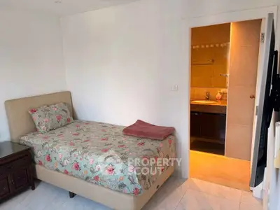 Cozy bedroom with floral bedding and ensuite bathroom in modern apartment.