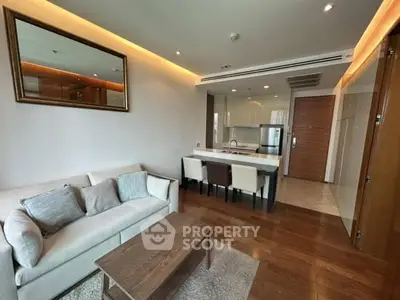 Modern open-plan living room with kitchen, featuring elegant decor and hardwood floors.