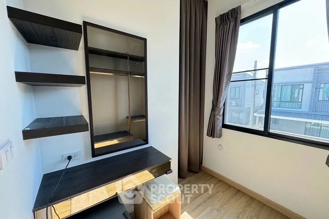 Modern study room with sleek desk and shelves, large window with natural light.