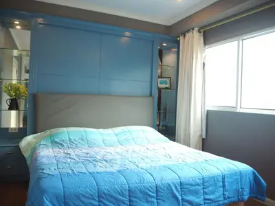 Spacious bedroom with modern blue decor and large window for natural light.