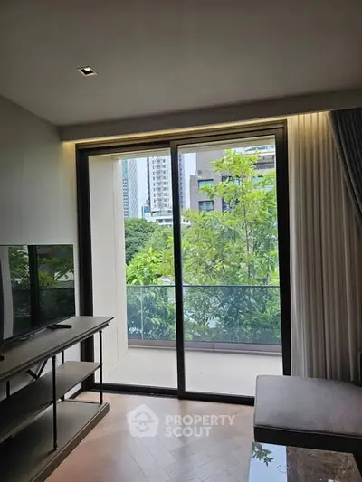 Modern living room with large glass doors opening to a balcony with city view.