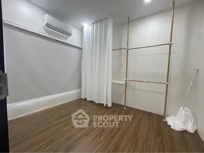 Spacious room with wooden flooring and air conditioning, perfect for versatile use.