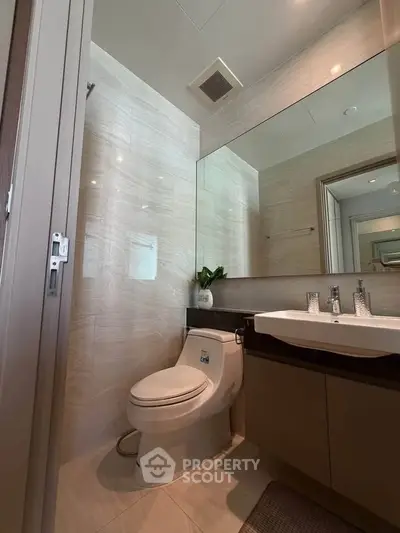 Modern bathroom with sleek fixtures and large mirror in a contemporary home.