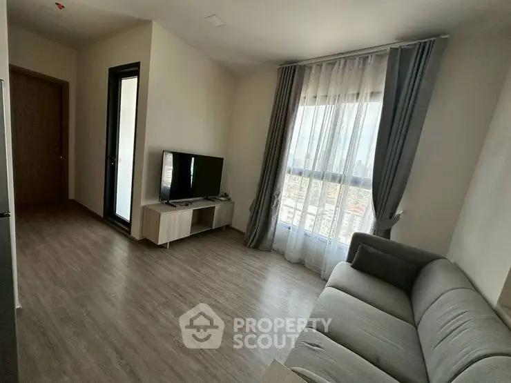 Modern living room with large window and stylish gray sofa