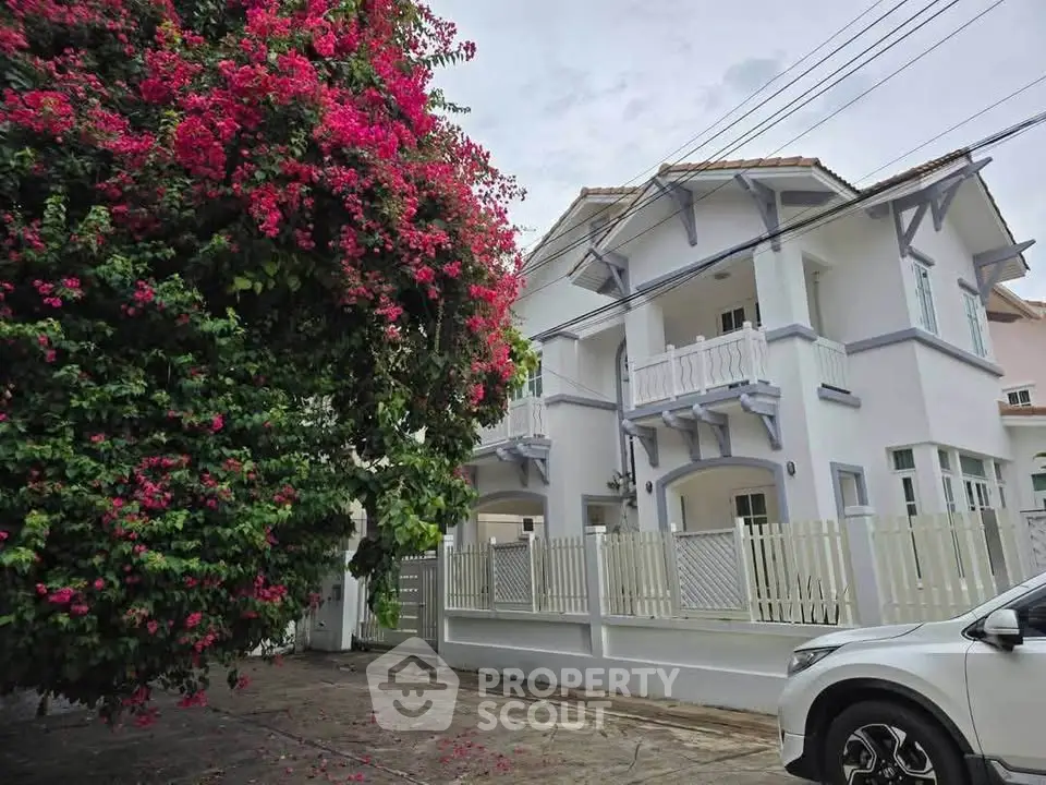 Charming two-story house with lush garden and white picket fence