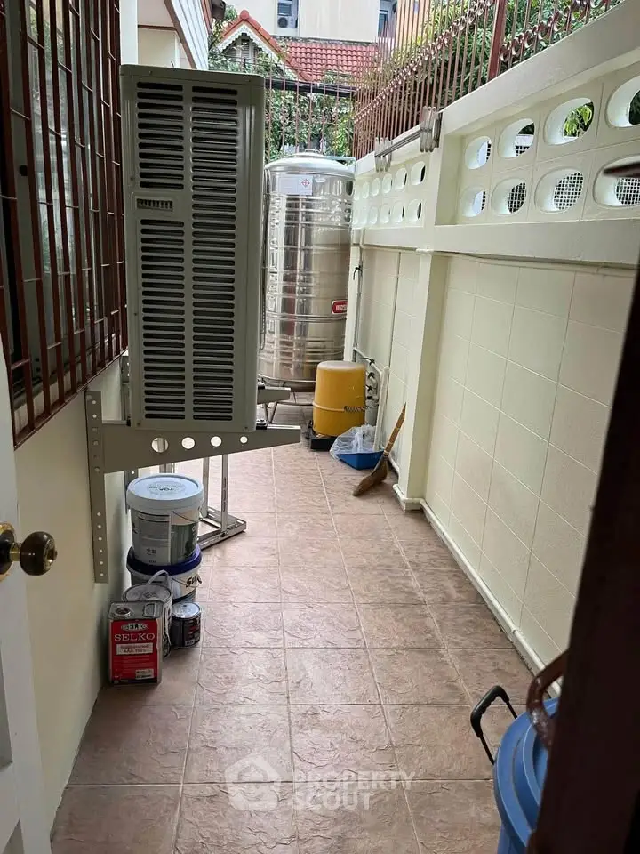 Outdoor utility area with water tank and air conditioning unit in a residential property.